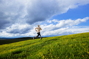 Wall Mural - Woman trail runner cross country running at high altitude flowering mountain