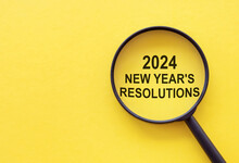 2024 New Year Resolution - Text Through Magnifying Glass On Yellow Background. Focus On New Goals