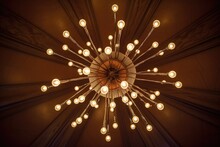 A Lit Chandelier Viewed From Directly Below Against A Cream Ceiling