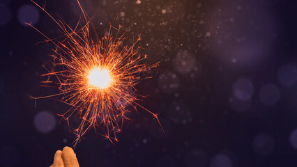 Canvas Print - Human hand holding sparkler with colorful blurred light