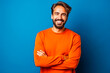 © Concept Photo Studio - Homme sympathique avec une barbe posant avec un pull orange sur un fond bleu