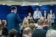 © Anton Gvozdikov - Back view of businessman asking question to speakers during conference at export forum