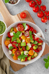 Wall Mural - Caprese salad with cherry tomatoes, mini mozzarella balls, avocado, pesto sauce and fresh basil. Healthy vegetarian meal.