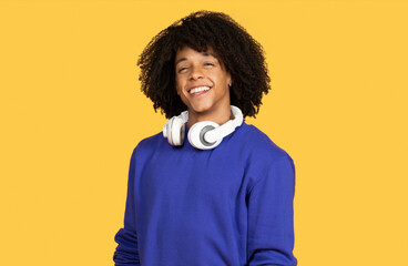 Wall Mural - Handsome Young Black Guy With Headphones Around Neck Posing Over Yellow Background