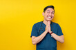 Hopeful professional young Asian male doctor or nurse wearing a blue uniform begging for help, pleading to God isolated on yellow background. Healthcare medicine concept