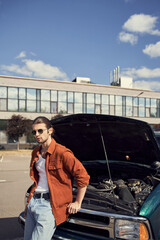 Wall Mural - vertical shot of attractive elegant man with dapper look standing near car with opened engine hood