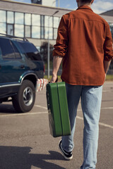 Wall Mural - cropped view of young stylish man in jeans and shirt holding petrol canister walking to his car