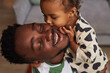 © Seventyfour - Close up portrait of Black little girl kissing father on cheek and smiling happily enjoying playtime together