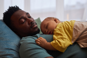 side view portrait of exhausted young father falling asleep with cute little baby on chest