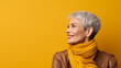 Kobieta w średnim wieku uśmiechnięta patrzy w lewą stronę na żółtym tle