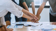 © amnaj - Top view of business people putting their hands on top of each other.