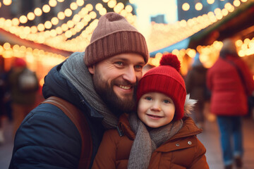 Wall Mural - Father and child having god time on traditional Christmas market on winter evening in town decorated with lights