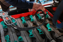 Forklift truck electric batteries being topped up at the regular maintenance check mans hand closeup with water hose