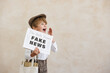 © Sunny studio - Newsboy shouting against grunge wall background. Boy selling fake news