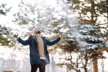 Wall Mural - Young stylish man in a snowy forest. Handsome man enjoying sunny winter weather. Concept of people, vacation.