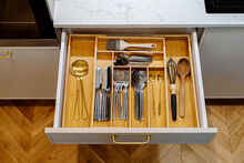 Open kitchen drawer with kitchenware and cutlery neatly organized. Storage organization system in kitchen