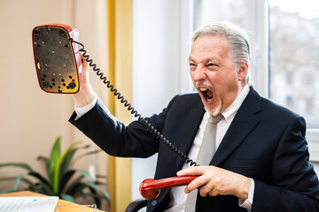 Wall Mural - Angry senior businessman launching his telephone