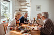 © Davor - Elderly friends share laughter and stories over a delightful meal