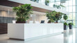 a white reception counter in a modern office building with a plant in the corner of the room and a large mirror
