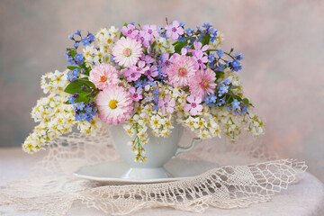 Poster - A bouquet of spring flowers: bird cherry, daisies, forget-me-nots in a cup on the table, a beautiful composition, still life, a holiday card.