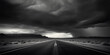 Dramatic black and white shot of a three-lane highway under a stormy sky, desolate and moody