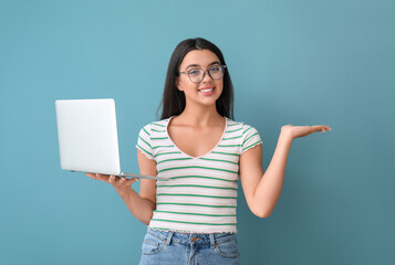 Wall Mural - Happy female programmer with laptop pointing at something on blue background