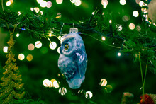 Christmas Toy Owl On A Christmas Tree With Blurred Sides From The Lights. Celebrating The New Year And Christmas
