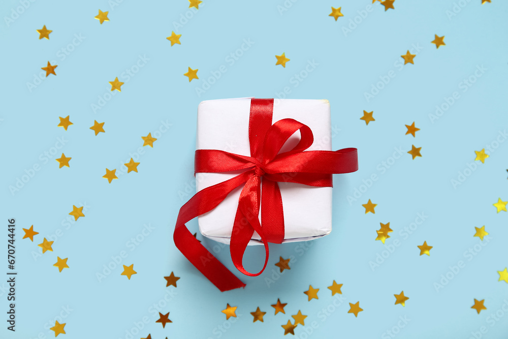 Christmas gift box and confetti on blue background