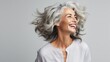 Joyful mature woman with flowing silver hair exudes happiness in a close-up portrait. Her radiant smile highlights her dental health, while her flawless skin 