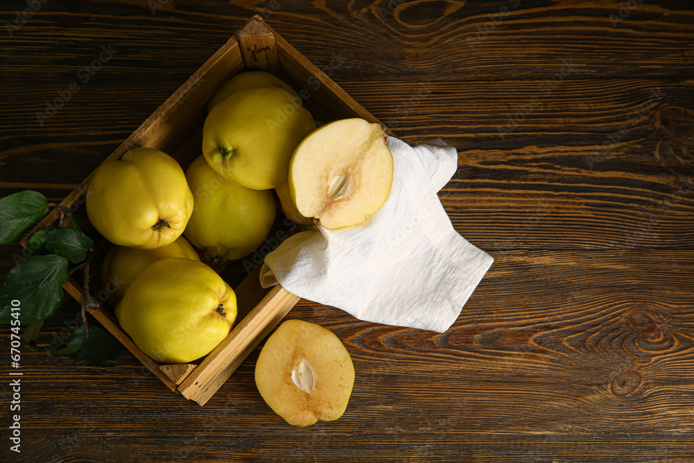 Box with sweet ripe quinces on wooden background