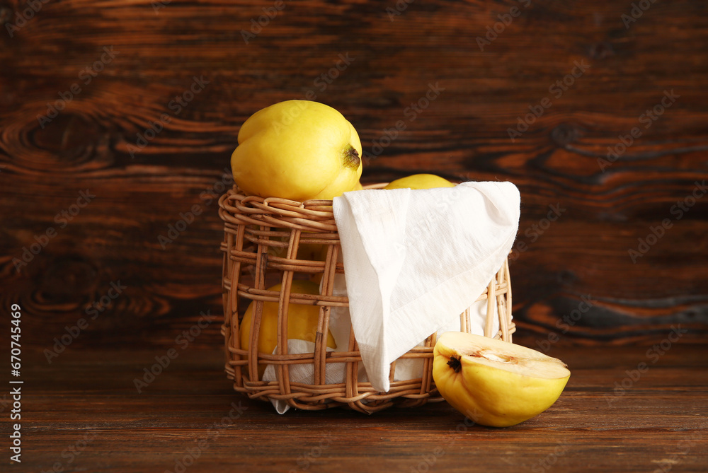 Wicker bowl with sweet ripe quinces on wooden background