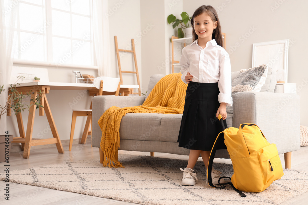 Cute little schoolgirl with backpack at home
