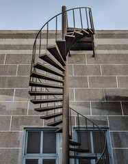 Wall Mural - Brown metal spiral staircase with iron railing lead down from Rooftop balcony to the first floor in front of brick textured wall. Selective focus.