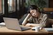 Exhausted Asian woman sits overworked needs rest fatigue taking nap near laptop. Tired Chinese girl