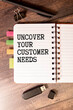 magnifying glass, plant, pen and a white notebook with the text uncover your customer needs