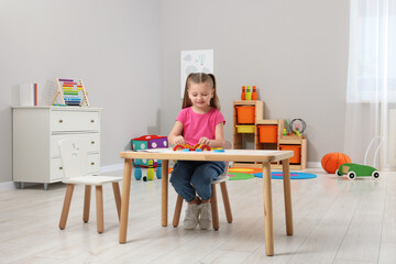 Wall Mural - Motor skills development. Girl playing with colorful wooden arcs at white table in kindergarten