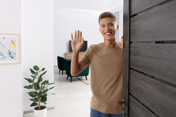 Wall Mural - Happy man waving near door, space for text. Invitation to come indoors