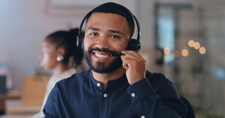 Portrait, smile and man at call center on headphones for crm support on bokeh at night. Face, happy sales agent on mic and telemarketing consultant, customer service professional or worker in office