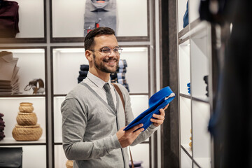 Wall Mural - A happy smart casual man is buying shirt in a boutique.