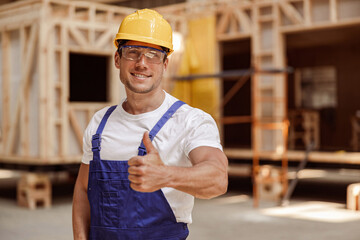 Wall Mural - Cheerful male worker in safety helmet giving thumbs up