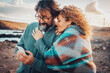 © simona - Man and woman using mobile phone connection online in outdoor travel leisure activity together. Happy adult couple enjoy technology and roaming communication. Travel adventure vacation lifestyle