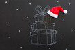 Stack of gifts drawn with chalk on blackboard with Santa Claus hat, creative concept christmas background