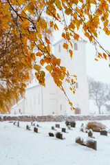 Wall Mural - Autumn birch leaves in front of Hoff Medieval Church, Toten, Norway, a snowy day in late October.