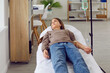 Child getting intravenous vitamin or medication therapy at clinic or hospital. Calm little girl lying on bed and receiving medical infusion through IV line. Medicine, health care, treatment concept