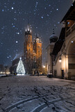 Fototapeta Miasto - Krakow, Poland, snowy Main Market square, St Mary's church and Cloth Hall in the winter season, during Christmas fairs decorated with Christmas tree