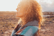 Side View Portrait Of Attractive Woman Closing Eyes And Enjoying Nature In Outdoor Leisure Activity Alone. People And Contemplation Meditation. Serene Lifestyle Female Person. Long Curly Healthy Hair