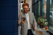 © Kostiantyn - Handsome sales manager with laptop standing on modern coworking background and use phone