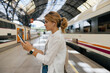 Profile portrait of lovely cute girl with collected hair standing in headphones with smartphone on the station 