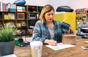 Woman entrepreneur checking return form of wrong package sent to client in online shop. Return policy and customer support in ecommerce concept. Young female reviewing refund product in small store.