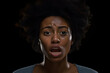 surprised and scared young adult African American woman, head and shoulders portrait on black background. Neural network generated photorealistic image. Not based on any actual person or scene.